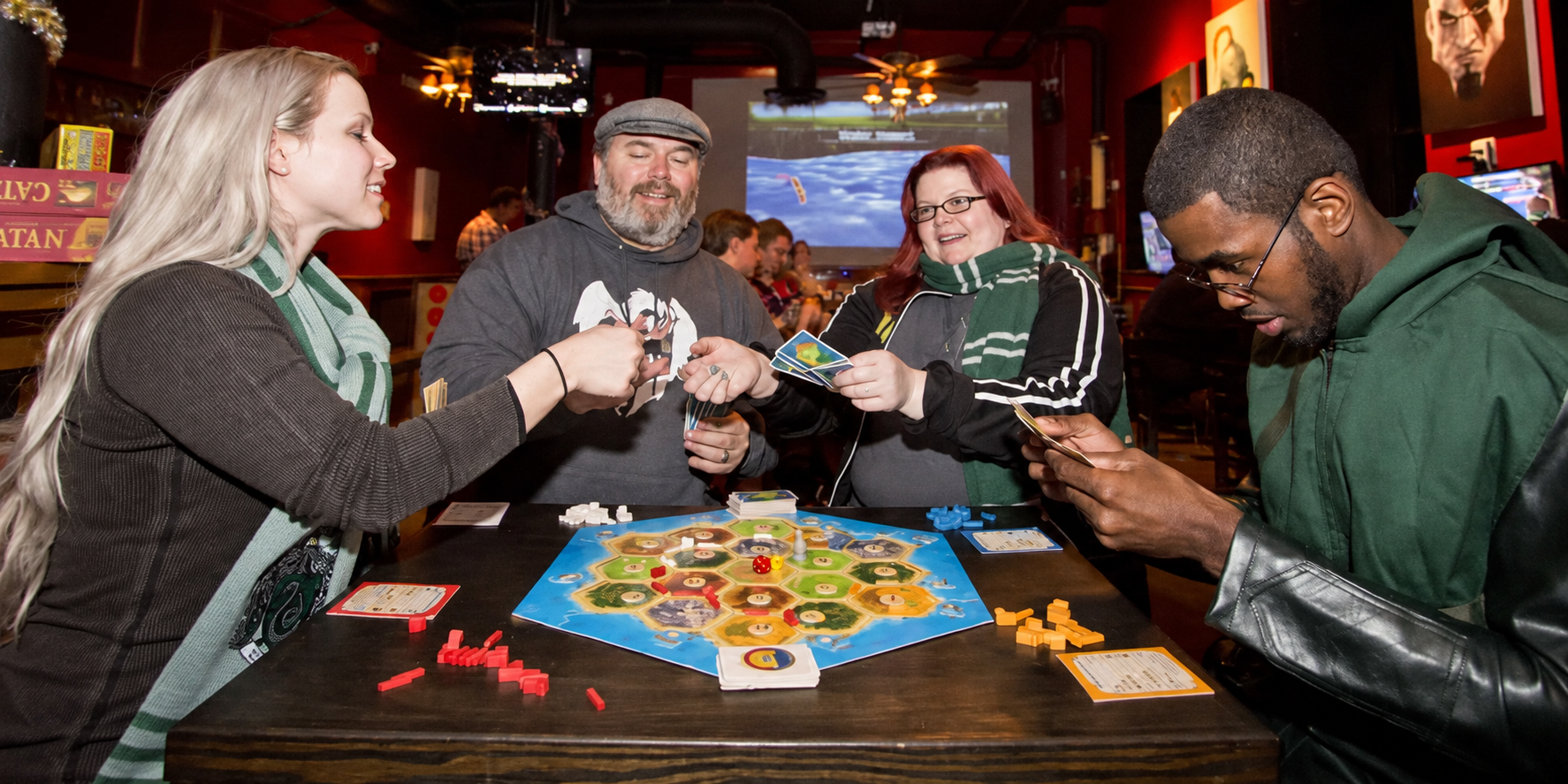 Lex and fellow gamers enjoying Catan around a table at The Chromatic Dragon